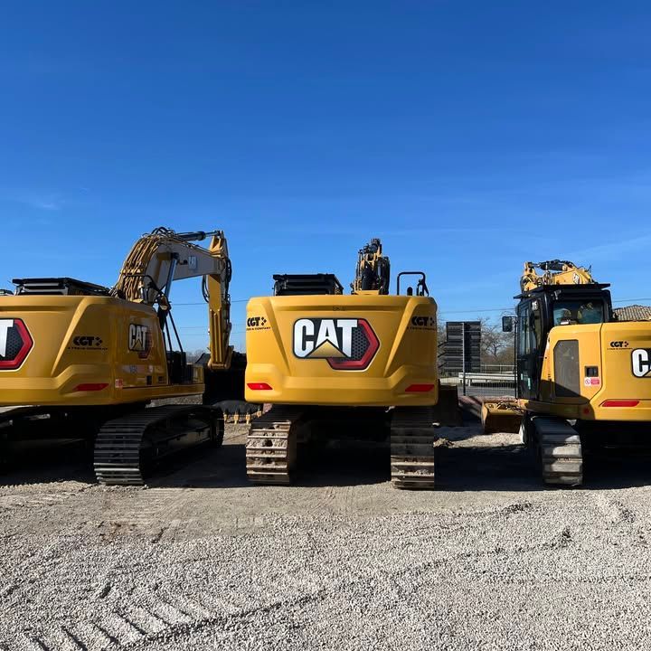 Tre escavatori Caterpillar gialli parcheggiati all'aperto in una giornata di sole.