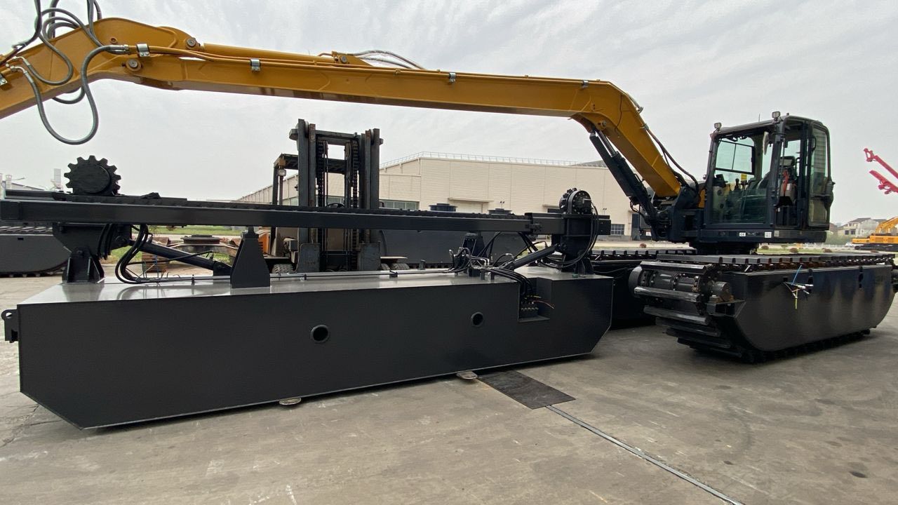 Escavatore nero su un pontone galleggiante, in azione su un corso d'acqua, con un braccio giallo.