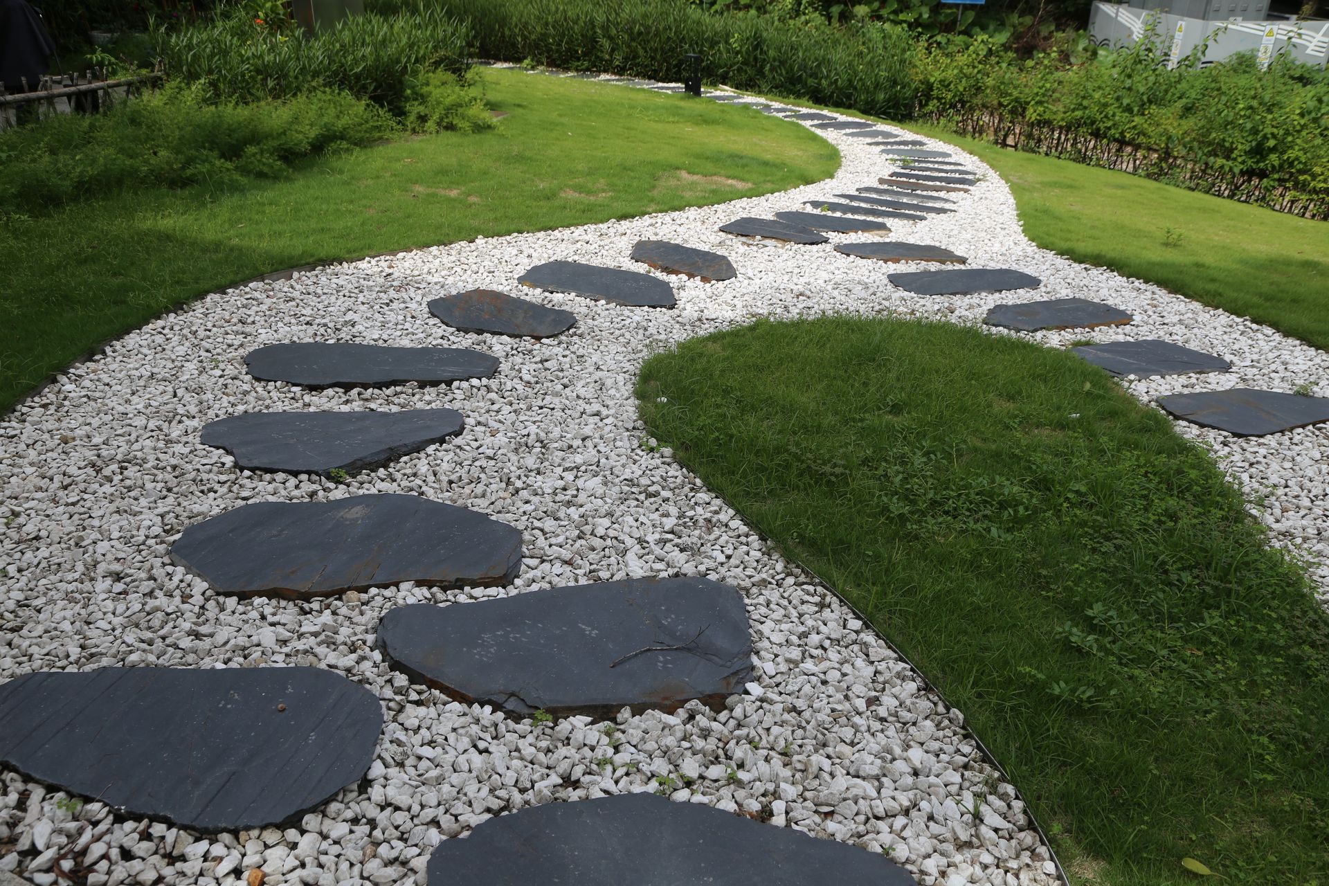 Sentiero in pietra con gradini in mezzo a ghiaia bianca ed erba.