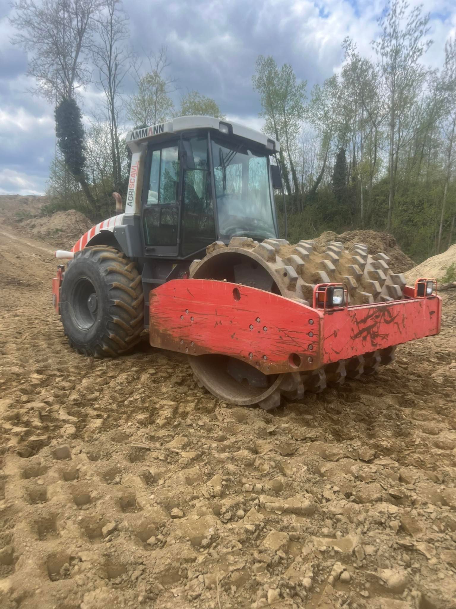 Compattatore di terra rossa e grigia sullo sporco, compattando il terreno.