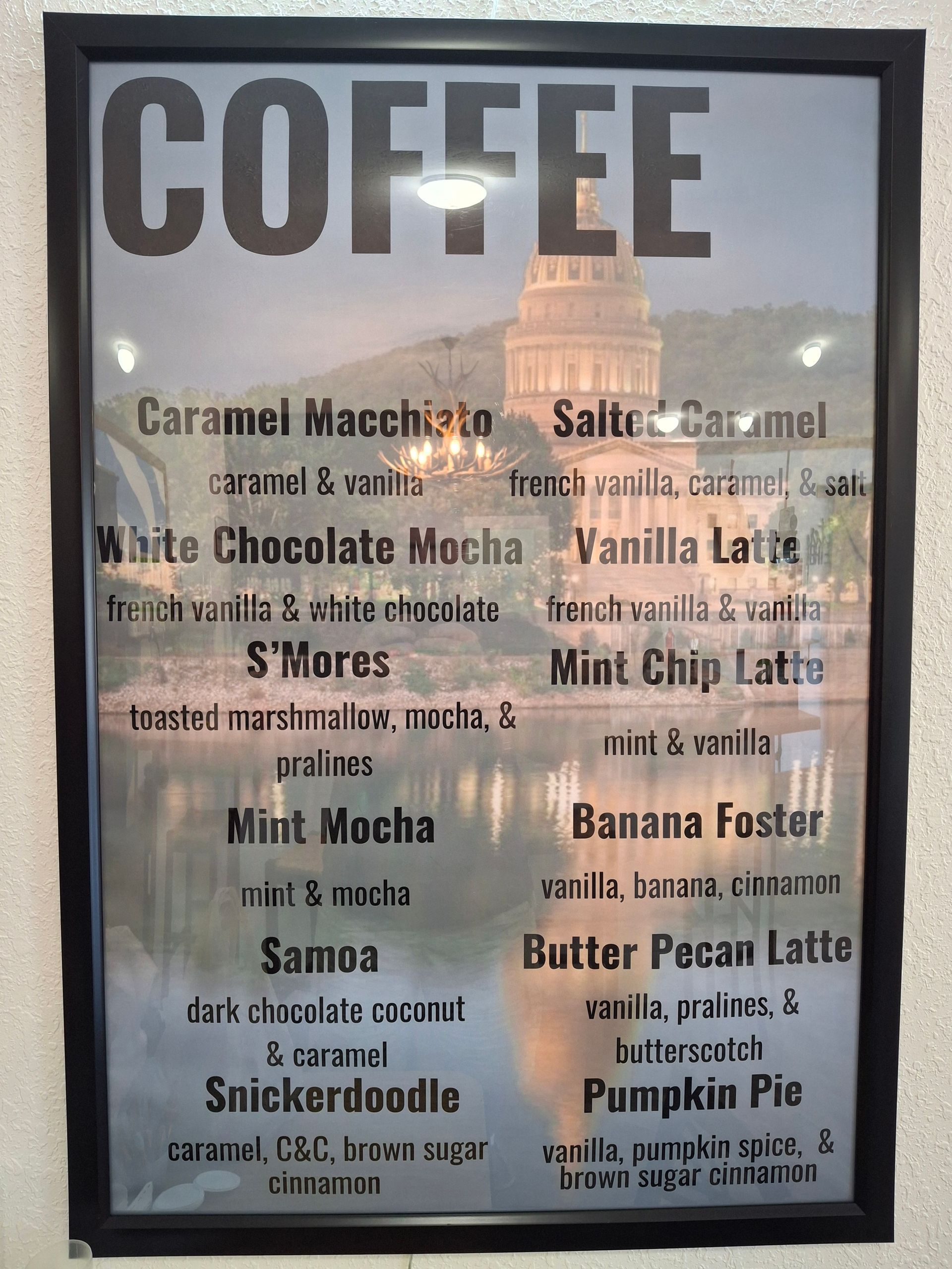 A coffee menu is displayed on a white wall