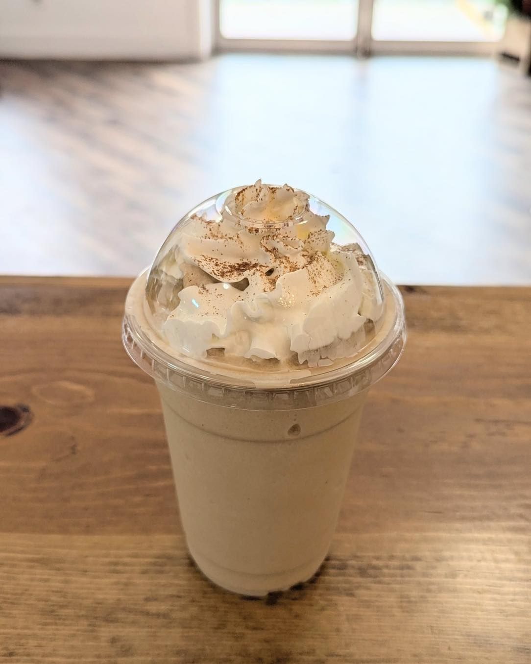 A milkshake with whipped cream in a plastic cup on a table.