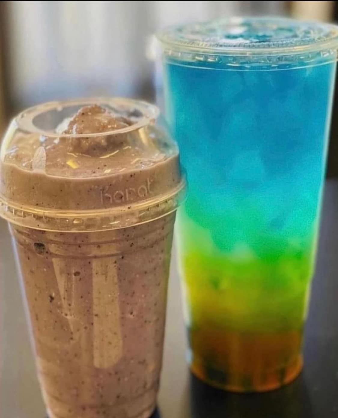 A glass of milkshake with a cookie on top on a wooden table.