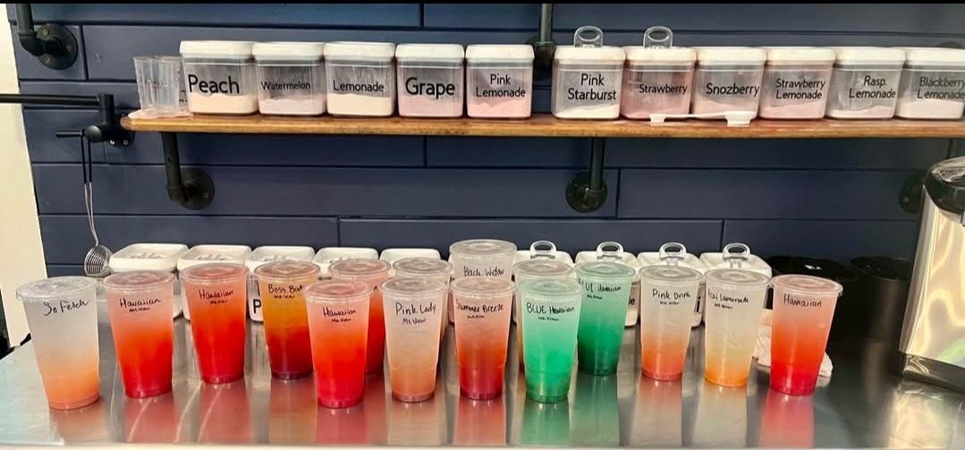 A close up of a pineapple and blueberry cocktail in a glass.