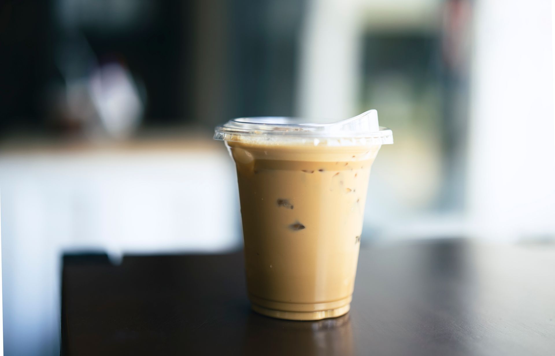 A cup of iced coffee is sitting on a wooden table.