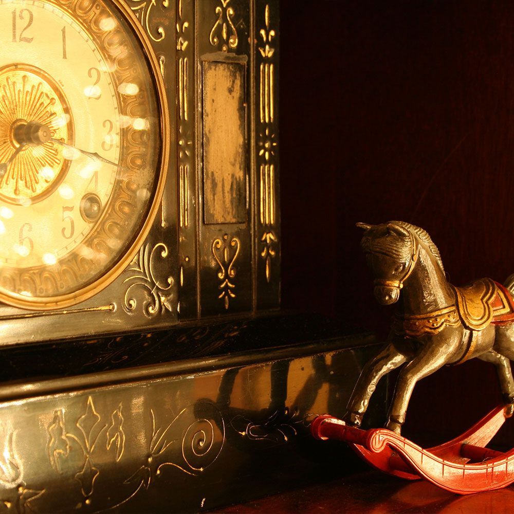 A clock with a rocking horse next to it