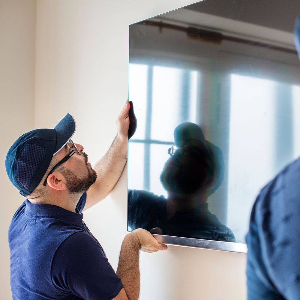 A man is installing a flat screen tv on a wall.