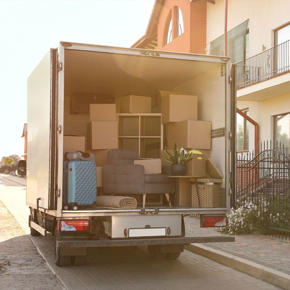 A moving truck filled with boxes and furniture is parked in front of a house.