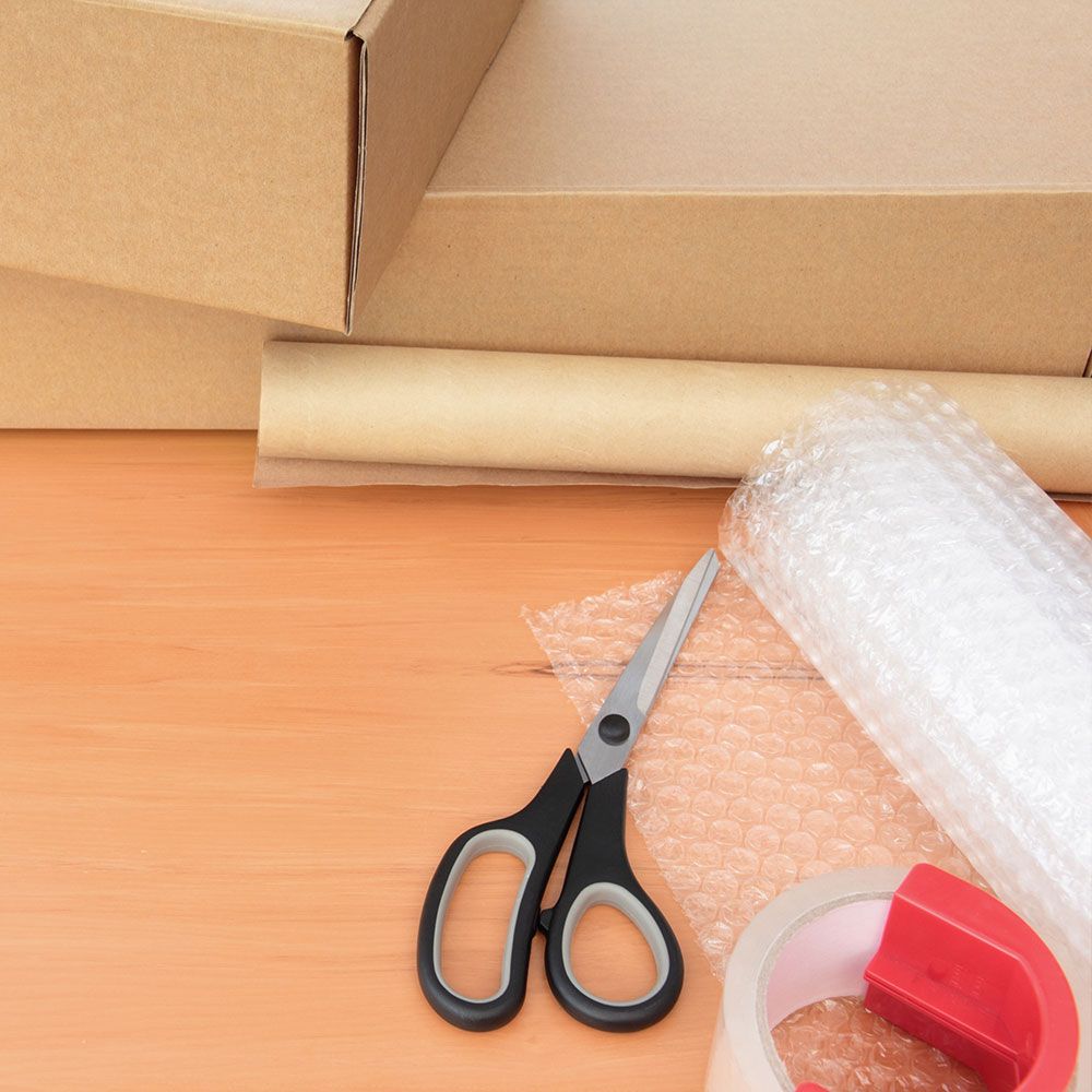 A pair of scissors sitting next to a roll of bubble wrap