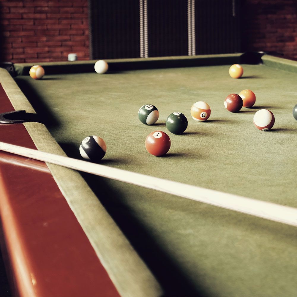 A pool table with balls and a cue on it