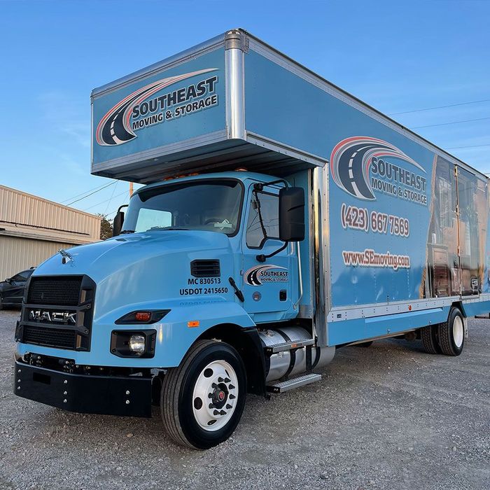 A blue mack truck is parked in a gravel lot.