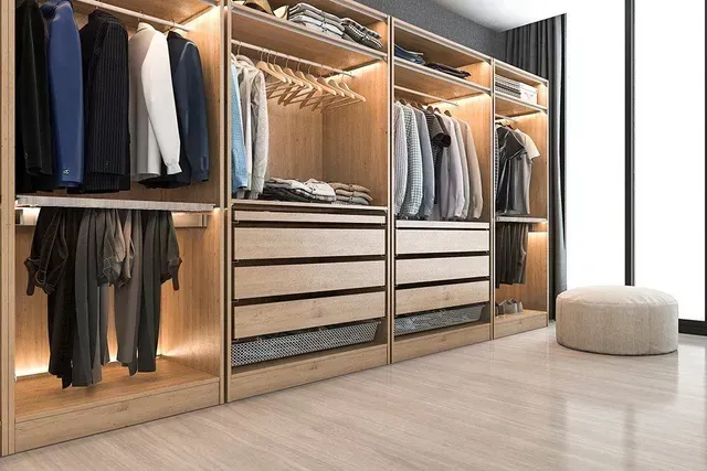 Empty walk-in closet with shelves and hanging rods. Neutral colors, recessed lighting.