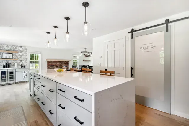 Kitchen corner with light wood cabinets, stainless steel appliances, and gray countertop.