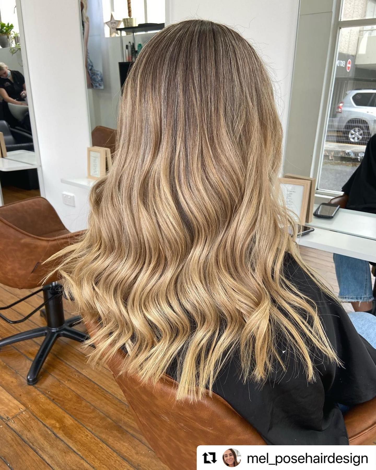 Long Wavy Blonde Balayage Hairstyle Viewed from Behind in A Salon Chair — Pose Hair Design in Orange, NSW