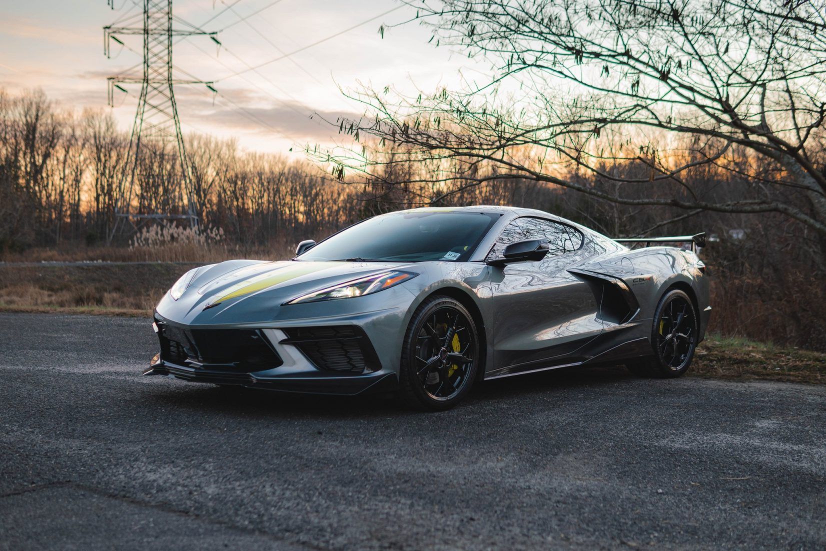 A silver corvette is parked on the side of the road.
