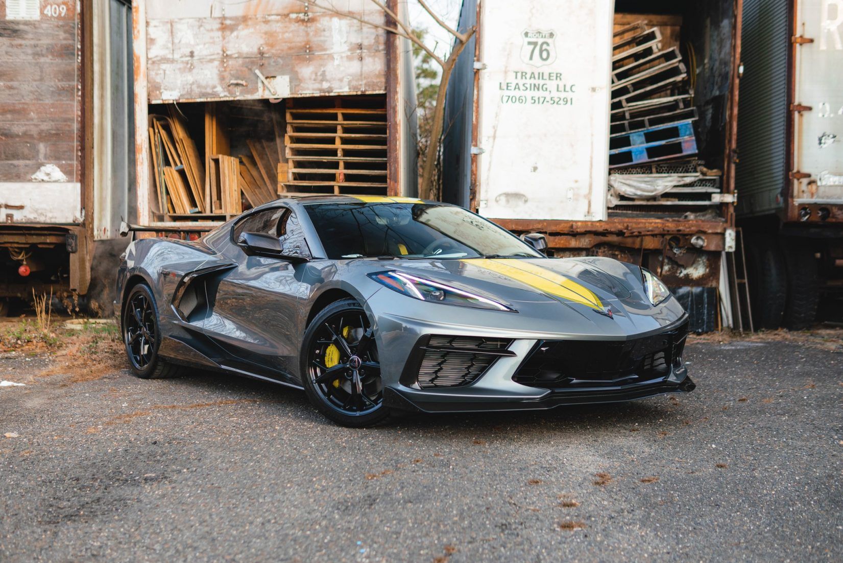 A gray and yellow sports car is parked in front of a building.