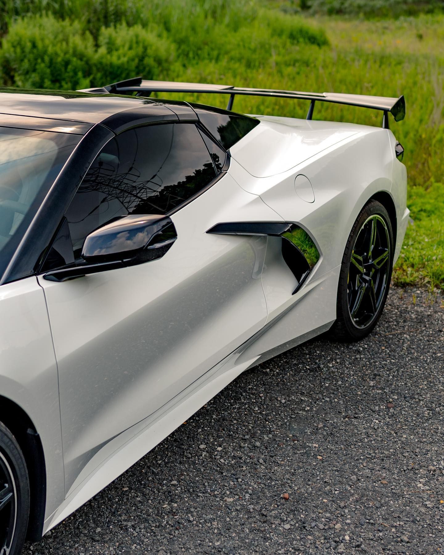 A silver corvette is parked on the side of the road.