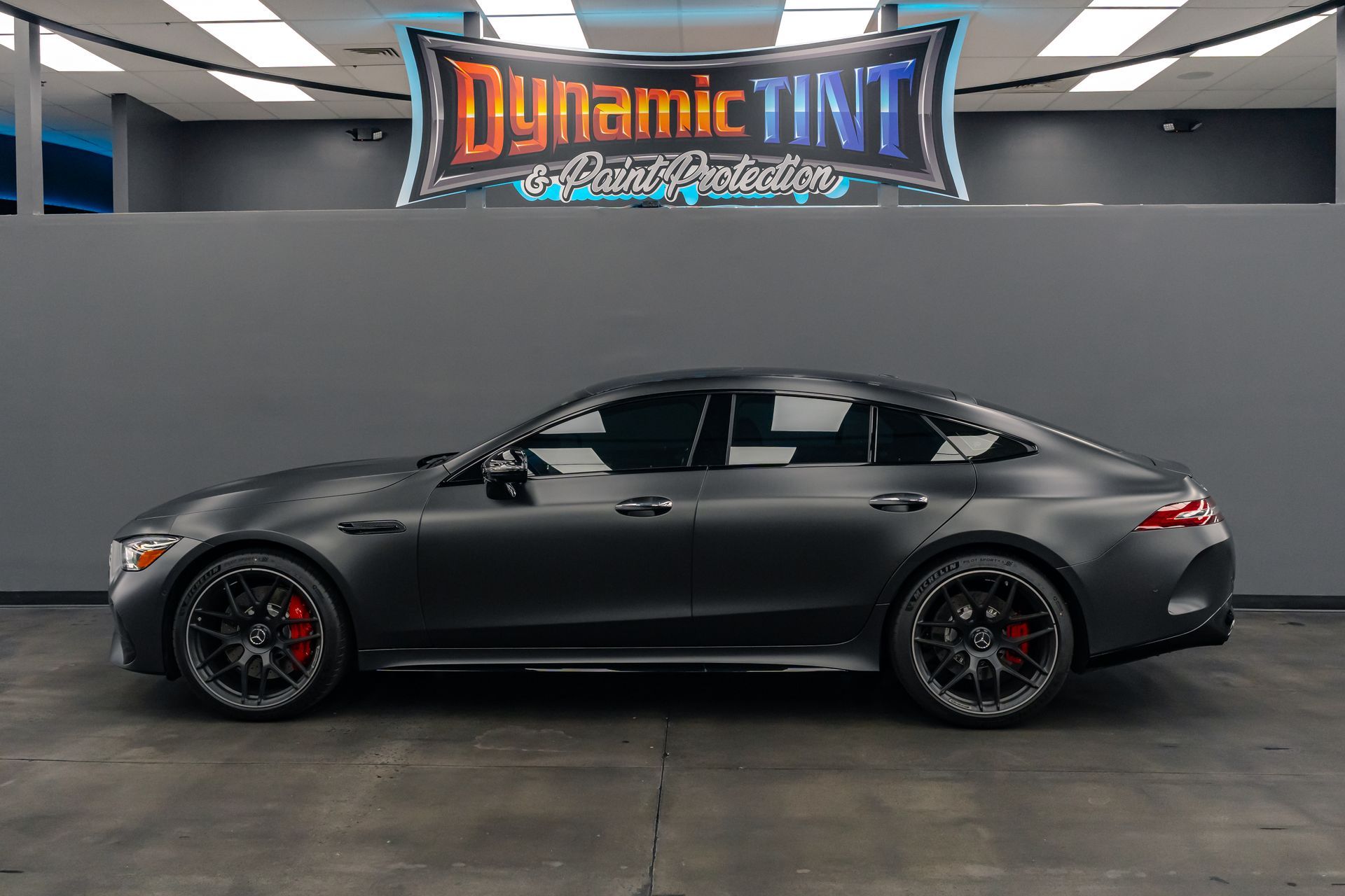 A black mercedes amg gt 63 s is parked in a showroom.