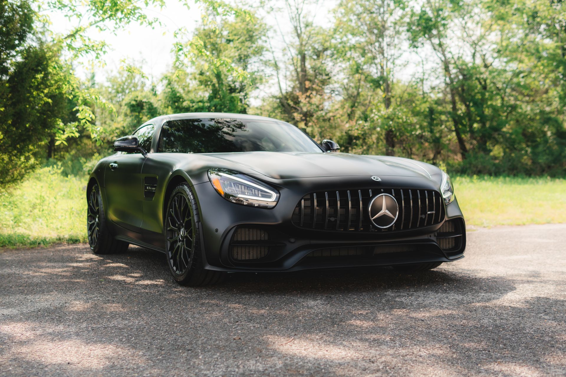 A black mercedes amg gt is parked on the side of the road.