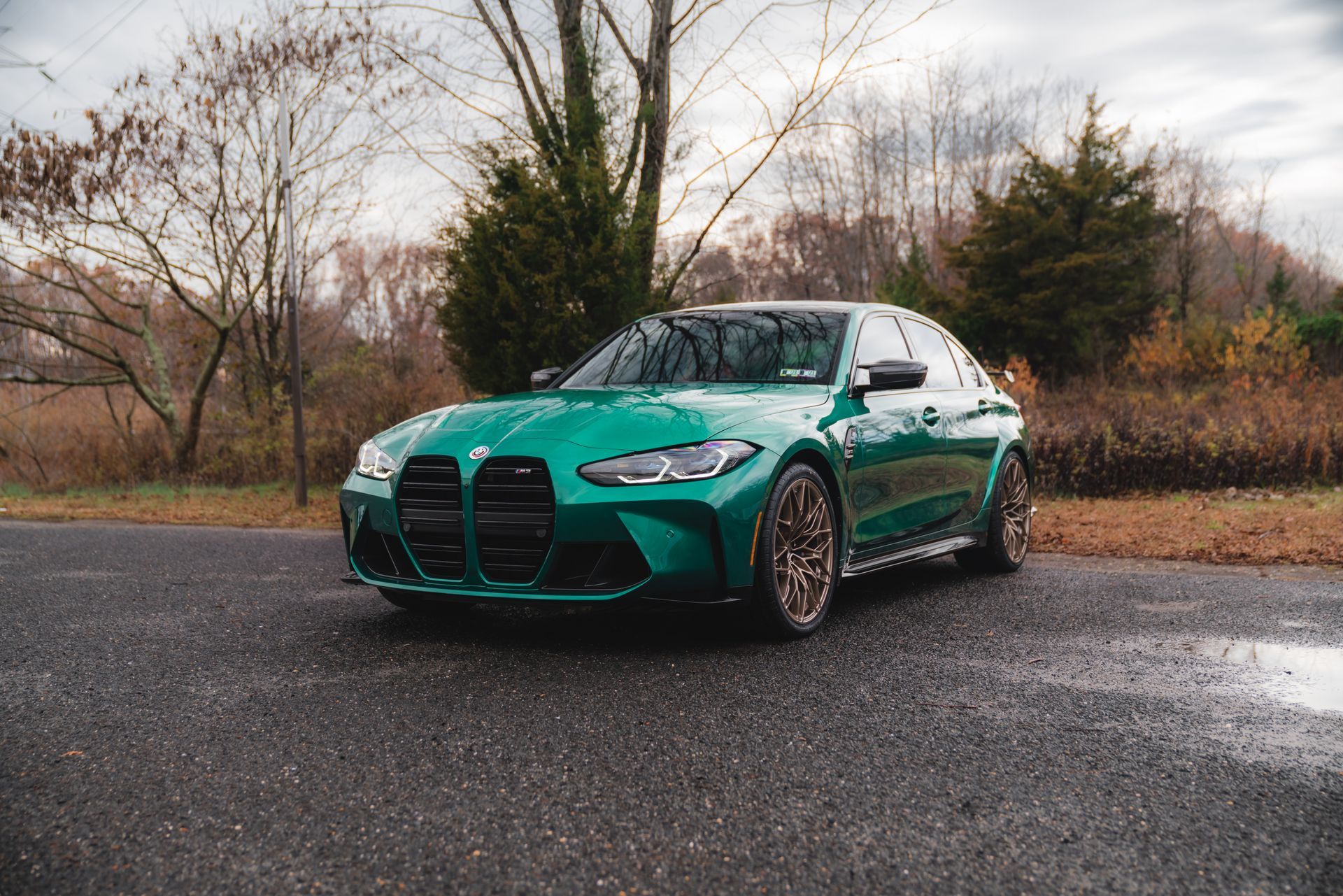A green bmw m3 is parked on the side of the road.