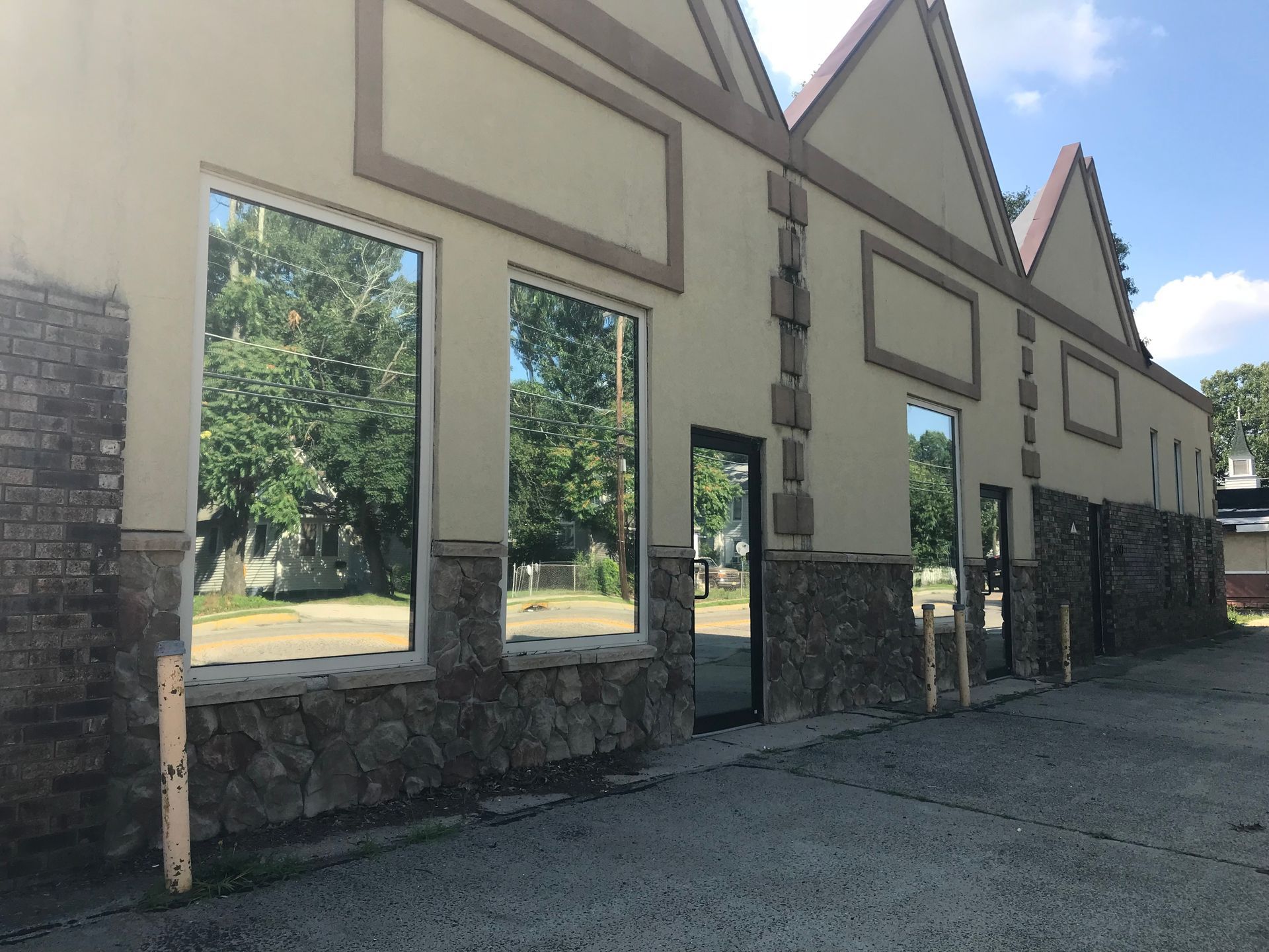 A large building with a lot of windows and trees reflected in the windows.