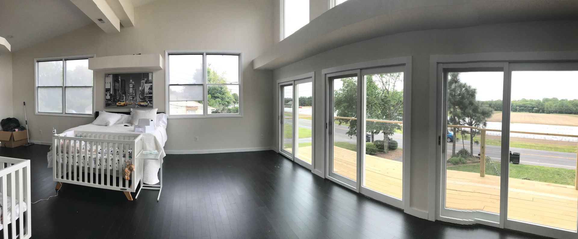 A large room with a lot of windows and a crib.