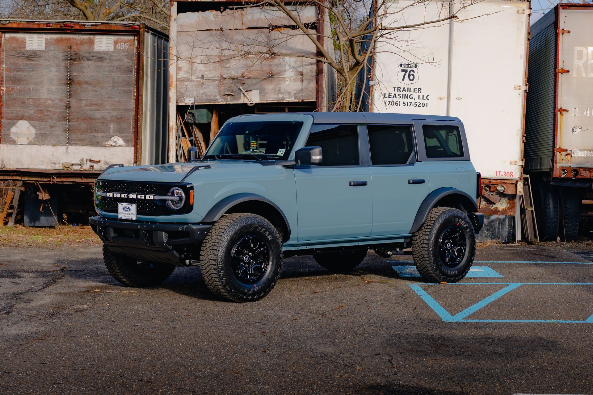 A blue ford bronco is parked in a handicapped parking spot.
