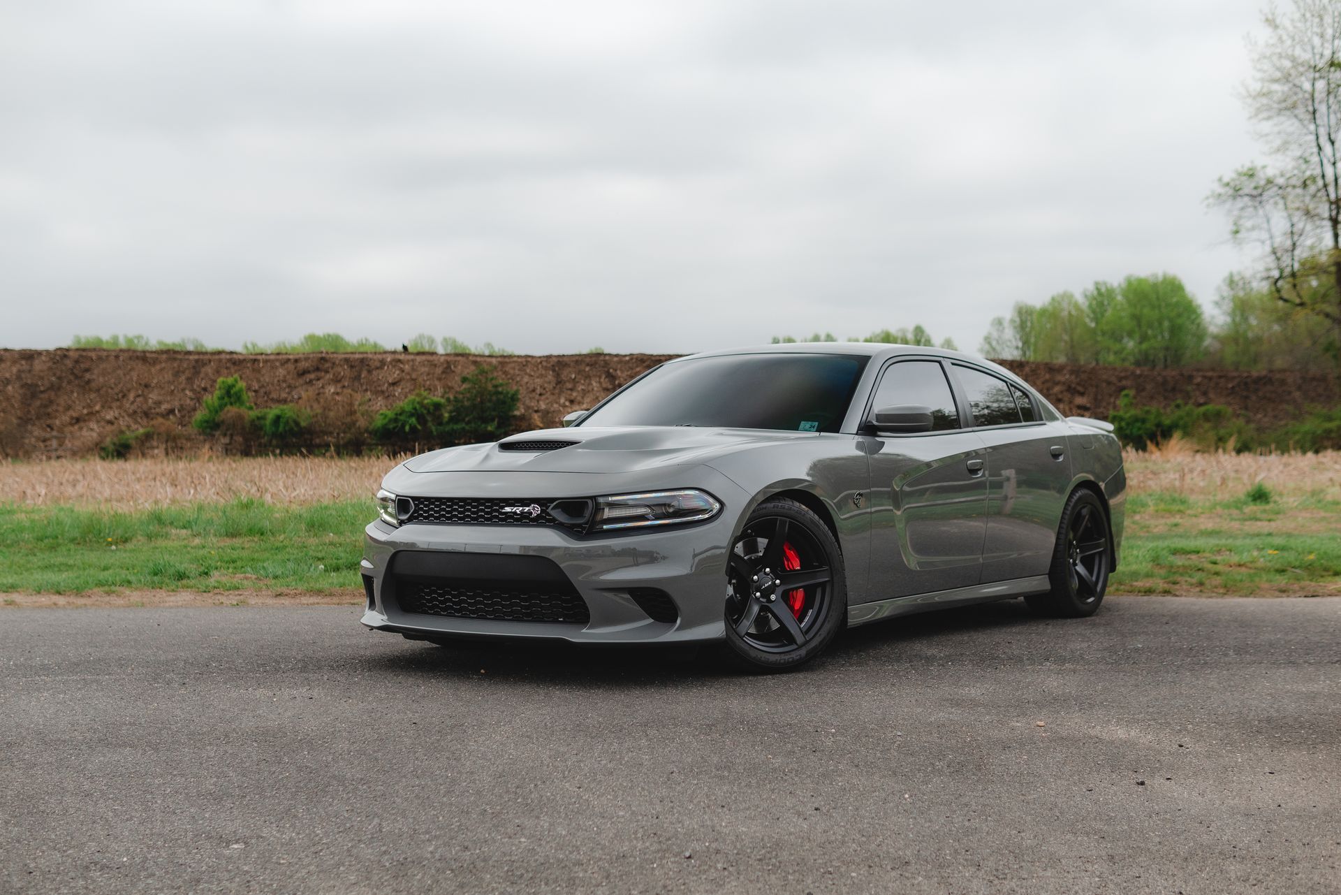A gray dodge charger is parked on the side of the road.