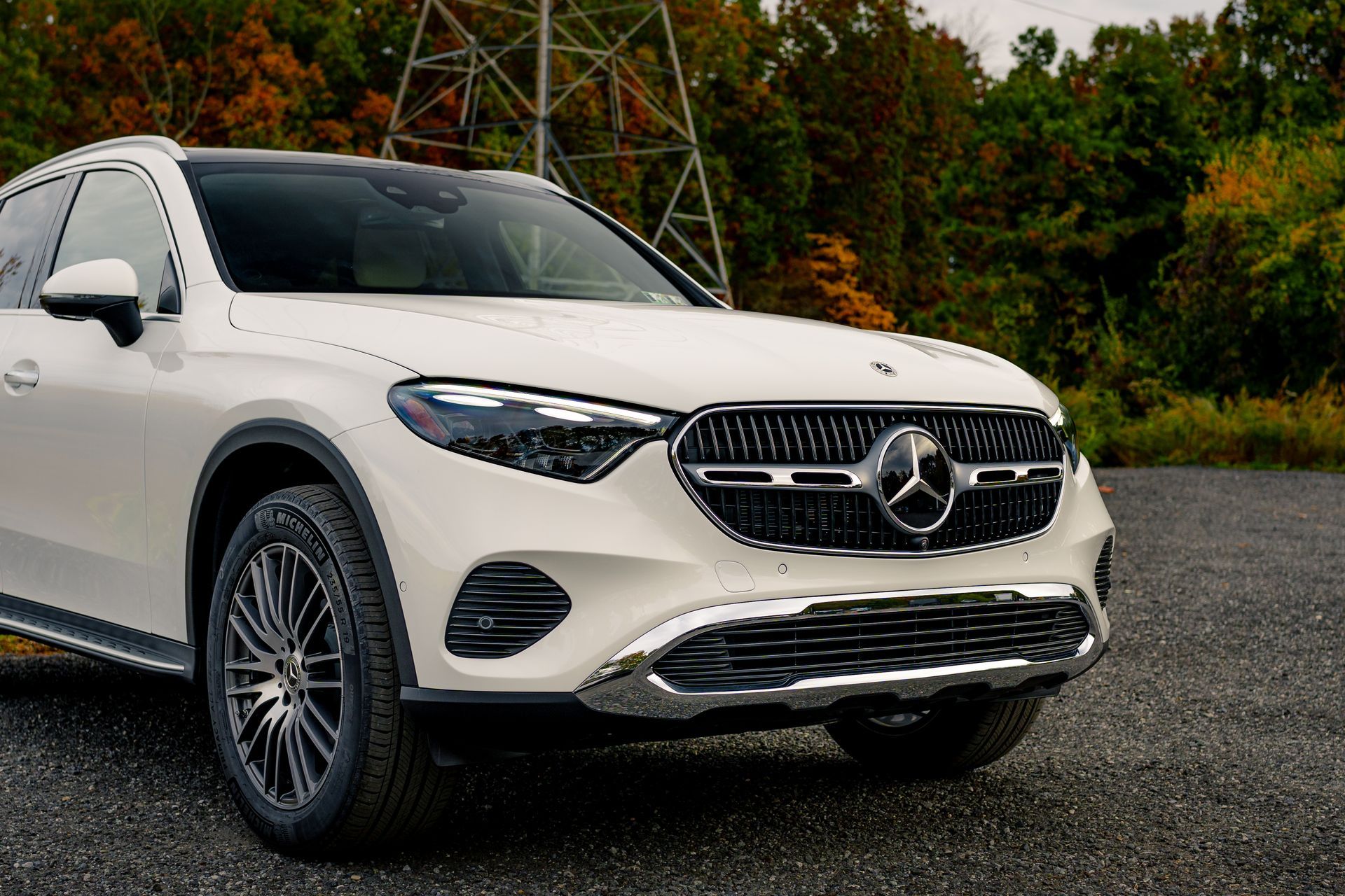 A white mercedes benz suv is parked in a gravel lot.
