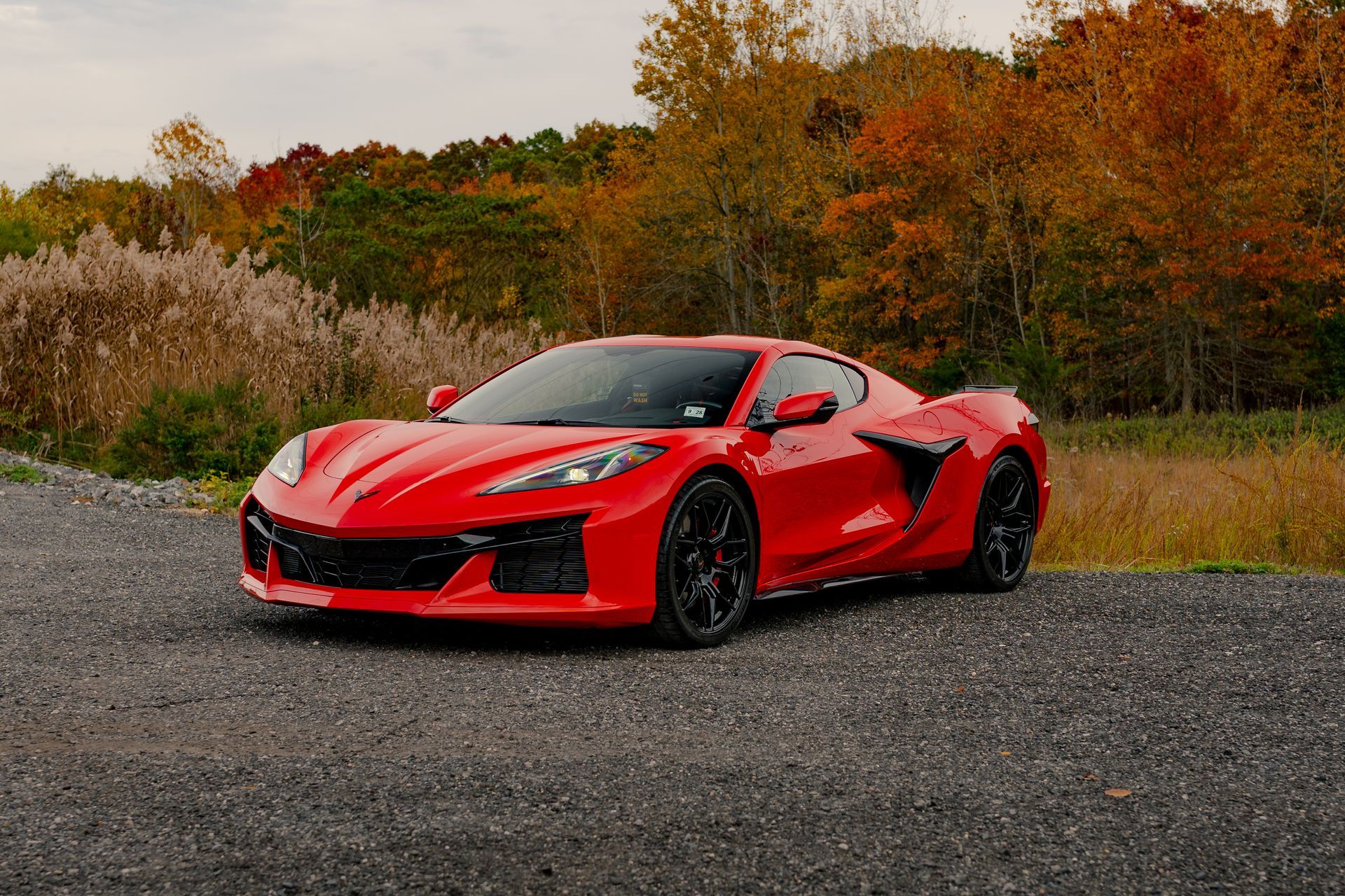 A red sports car is parked on a gravel road.