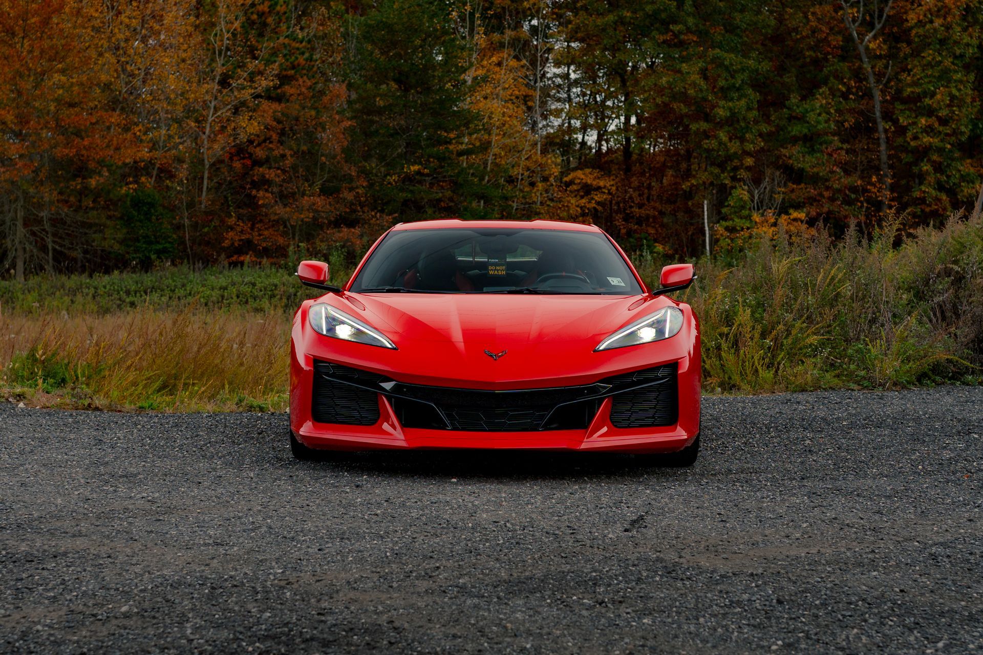 A red sports car is parked on the side of a gravel road.