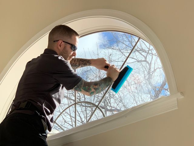 A man is cleaning a window with a brush.