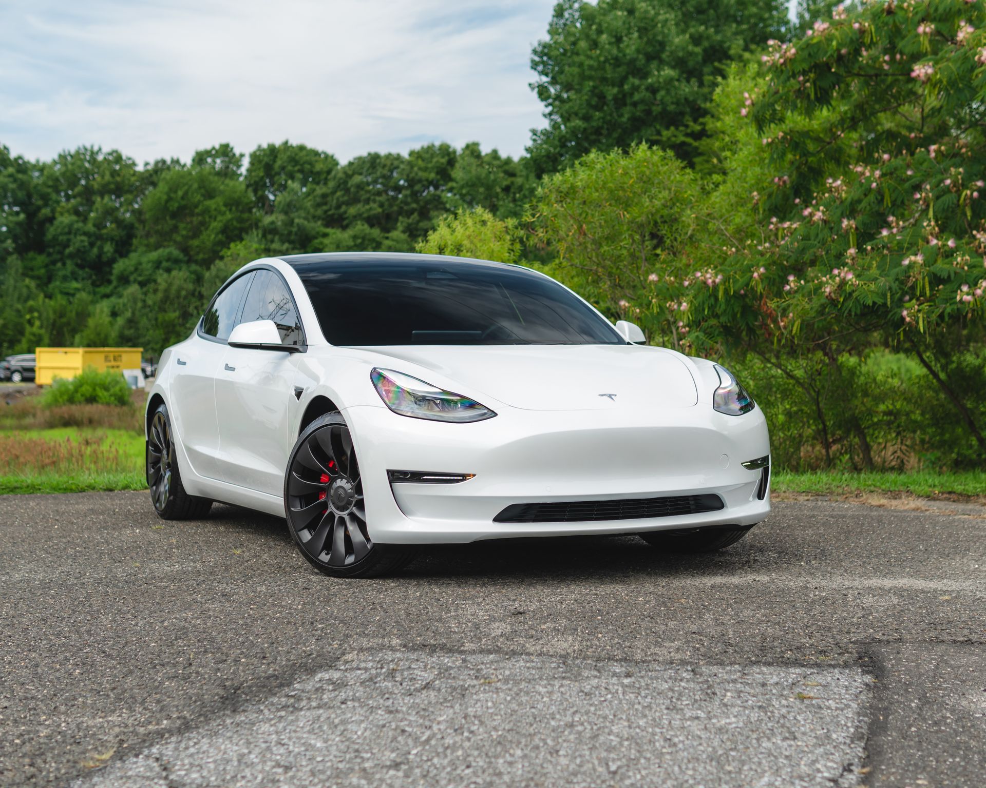 A white tesla model 3 is parked in a parking lot.