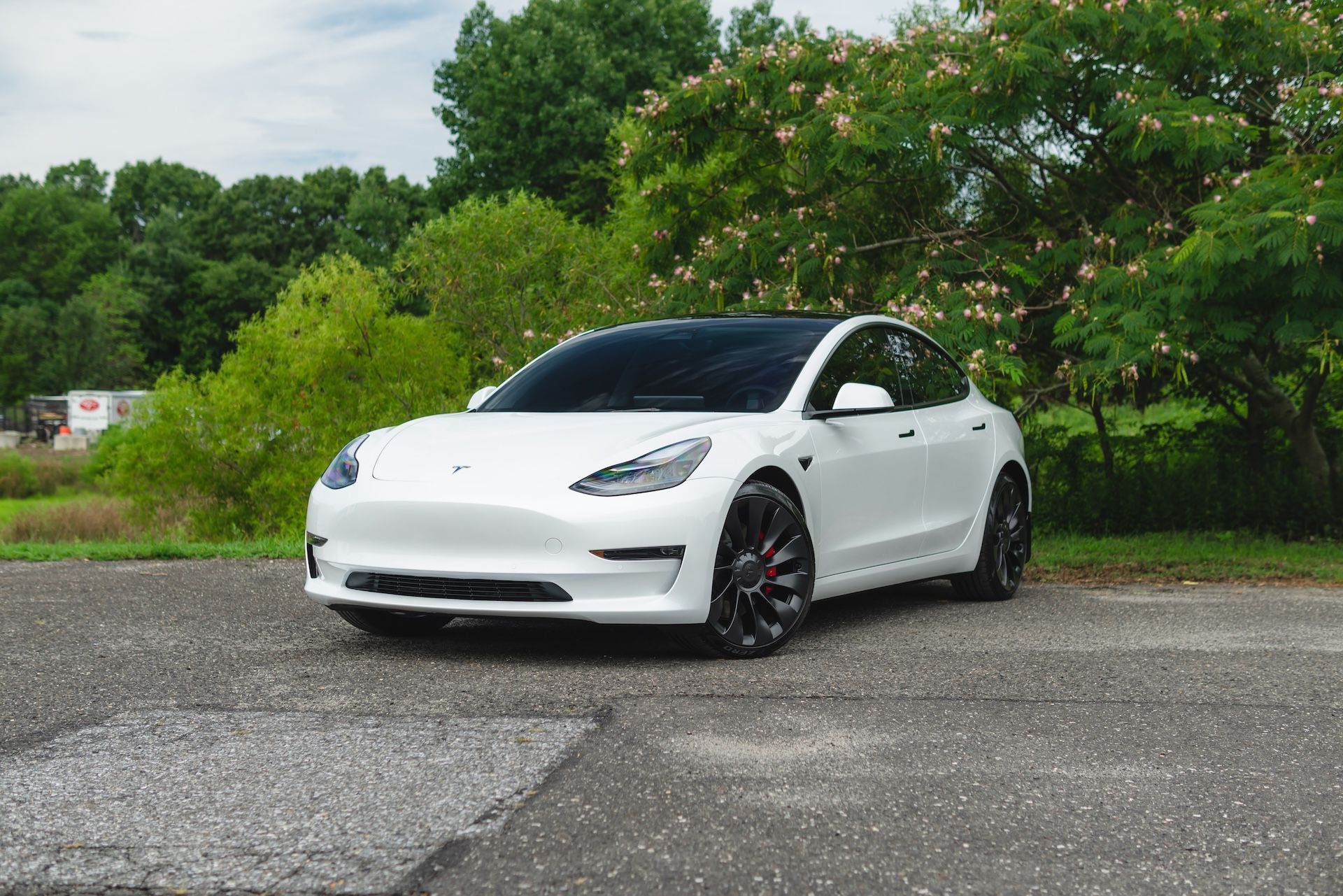 A white tesla model 3 is parked in a parking lot.