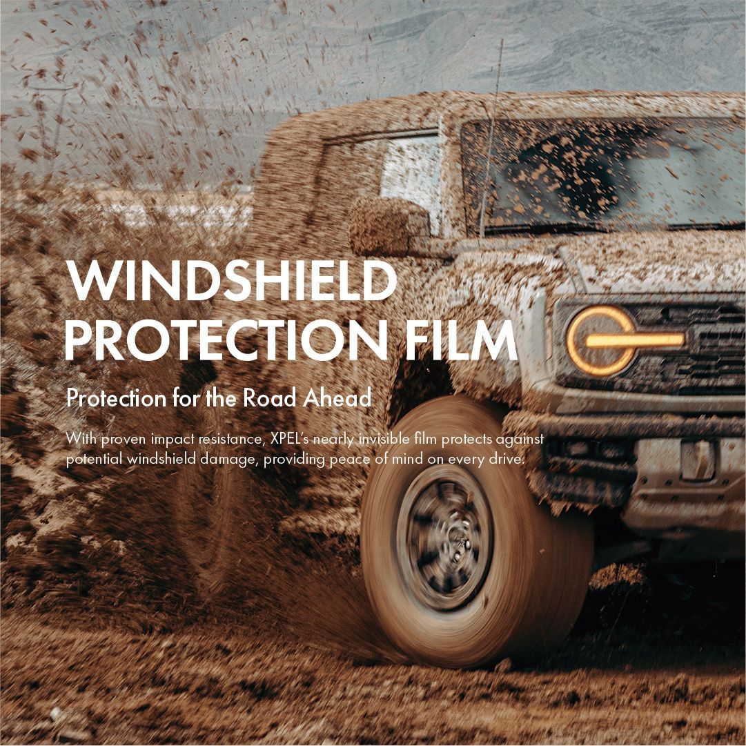 A truck is covered in mud and windshield protection film