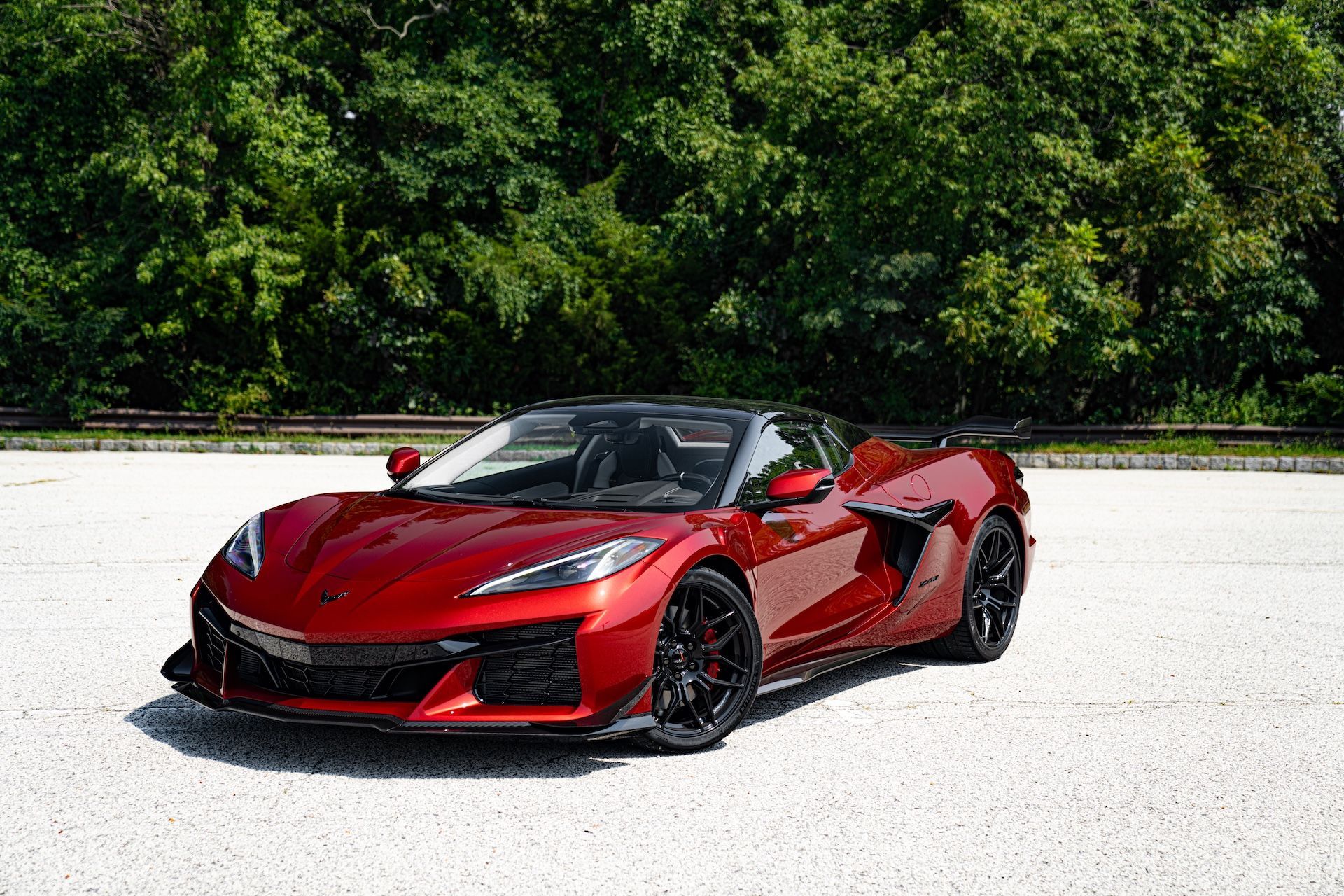 A red sports car is parked on a gravel road.