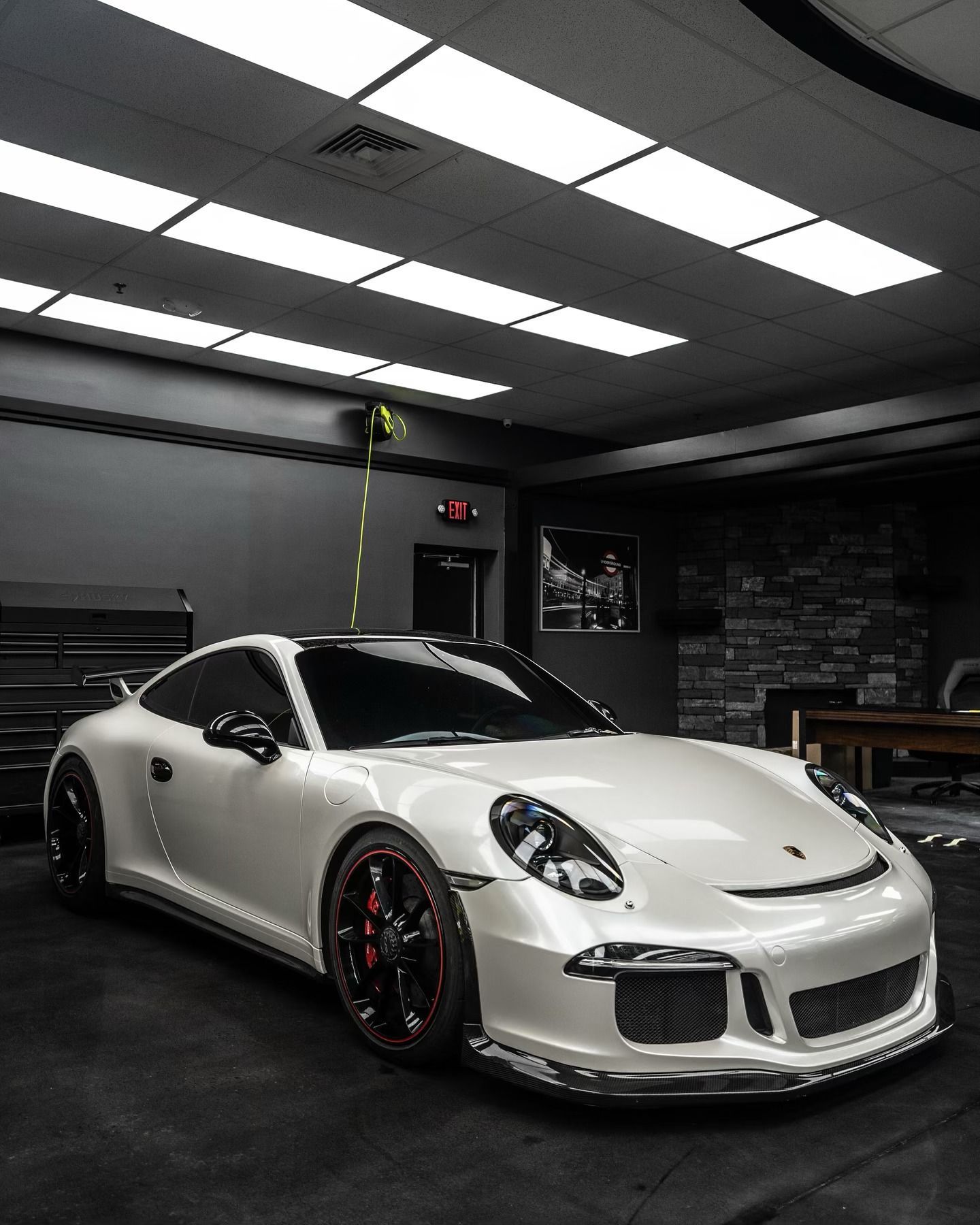 A man is cleaning the hood of a car with a wiper blade.