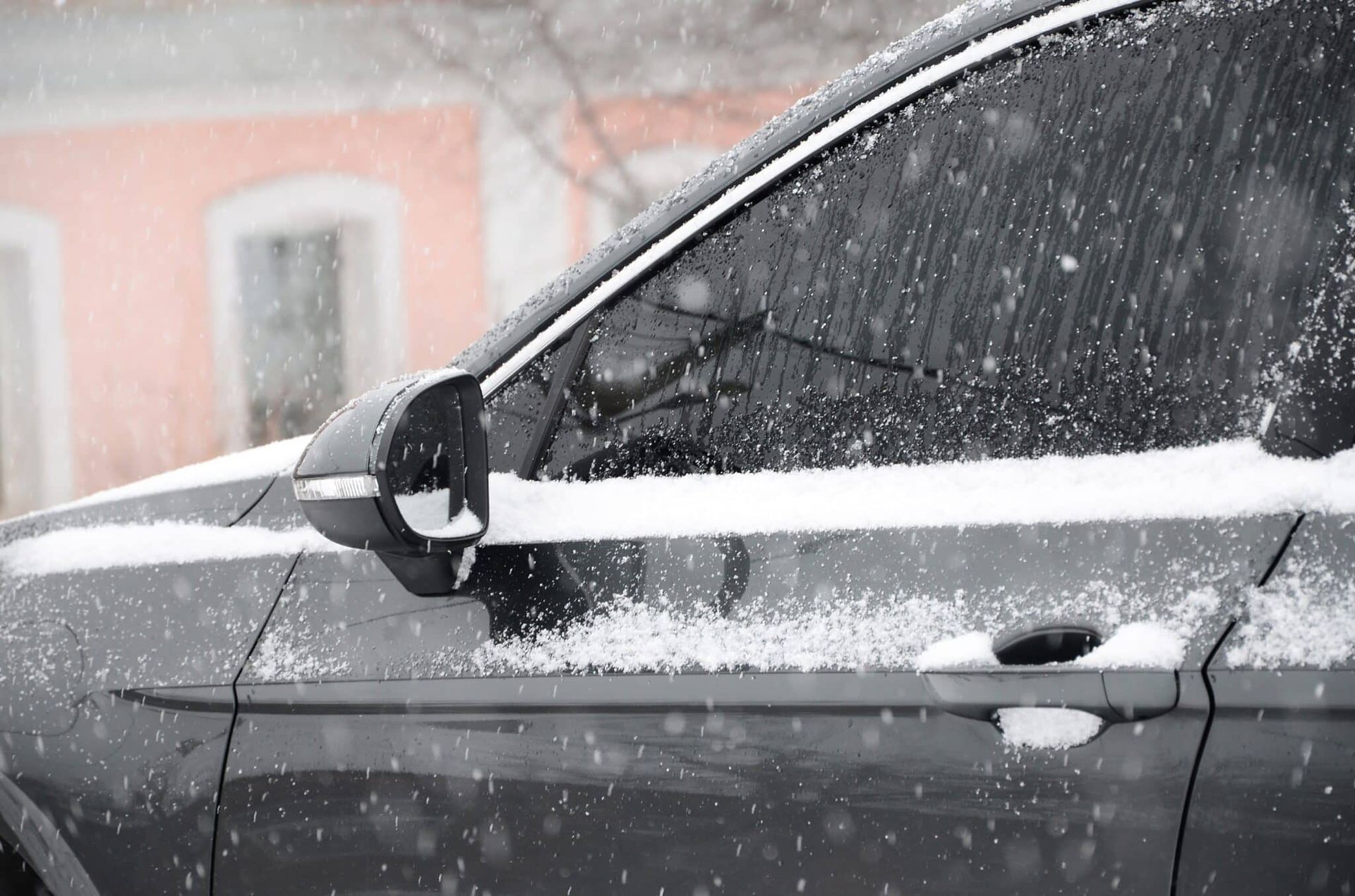 A car is covered in snow on a snowy day.