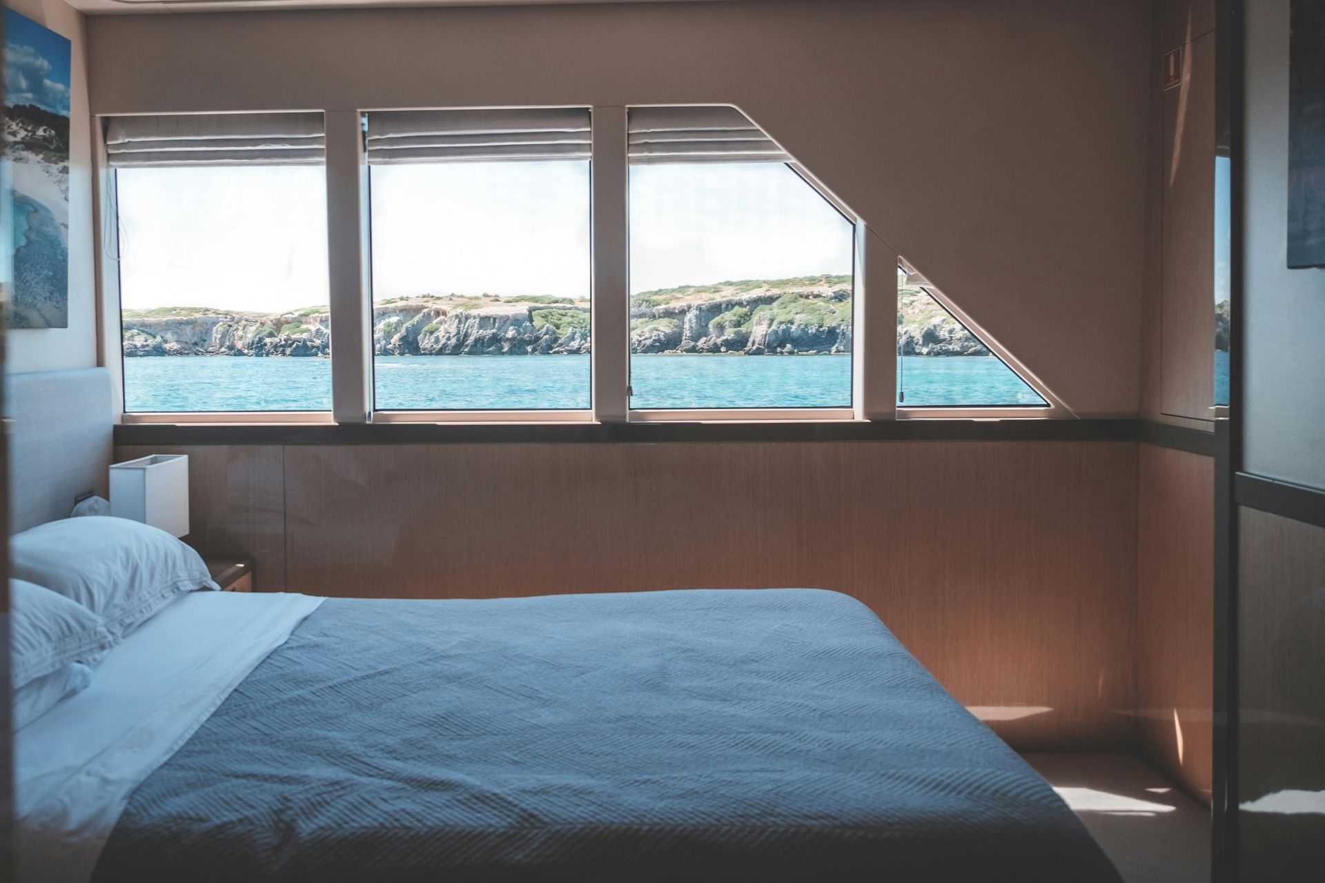 A bedroom with a bed , two windows and a view of the ocean.