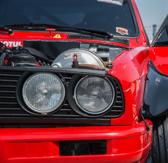 Close-up of a red sports car front with exposed engine and twin round headlights