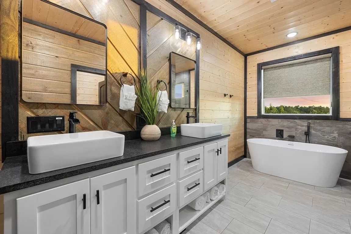 A bathroom with two sinks , a tub and two mirrors.