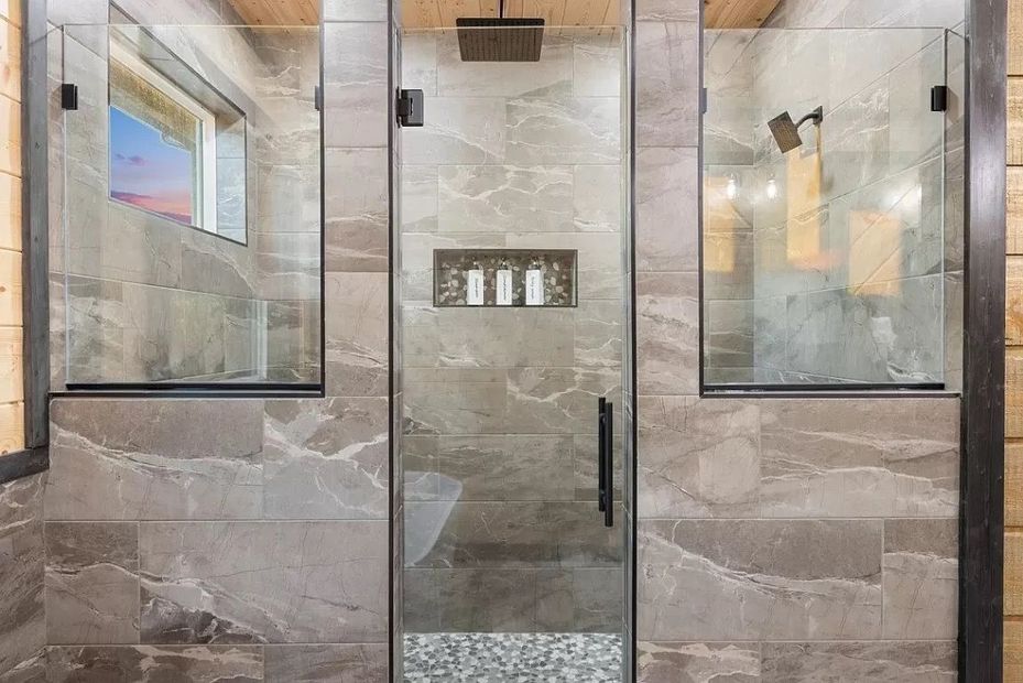 A bathroom with two walk in showers and a glass door.