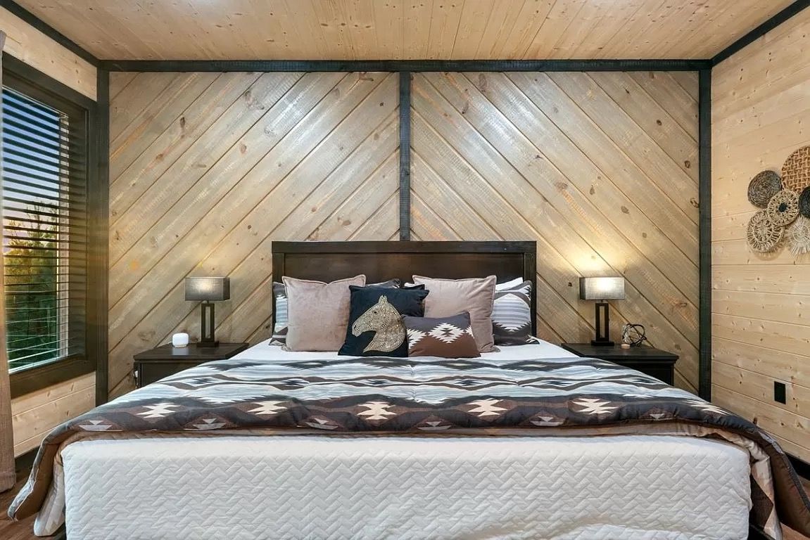A bedroom with a king size bed and wooden walls.
