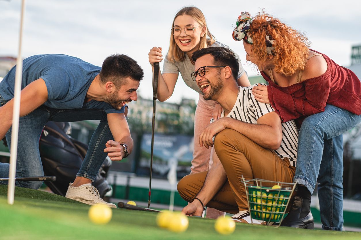 A group of young people are playing a game of mini golf.