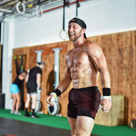 A shirtless man is standing in front of a wall with the letter j on it