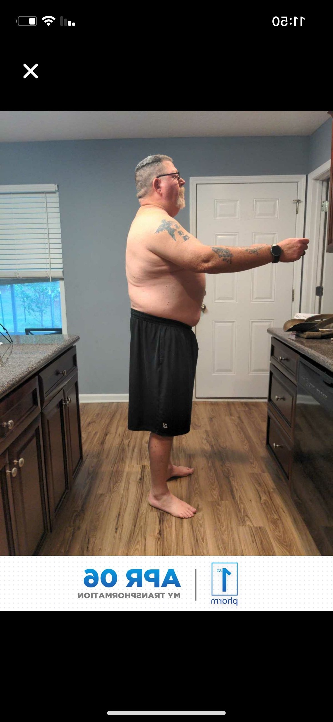 A shirtless man is standing in a kitchen.