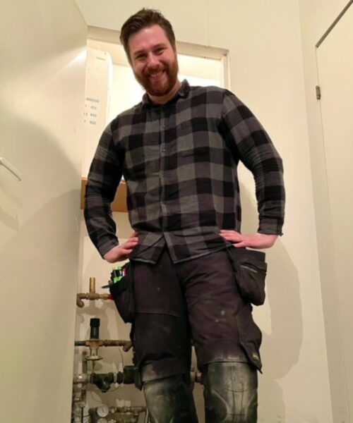 A man in a plaid shirt is standing with his hands on his hips