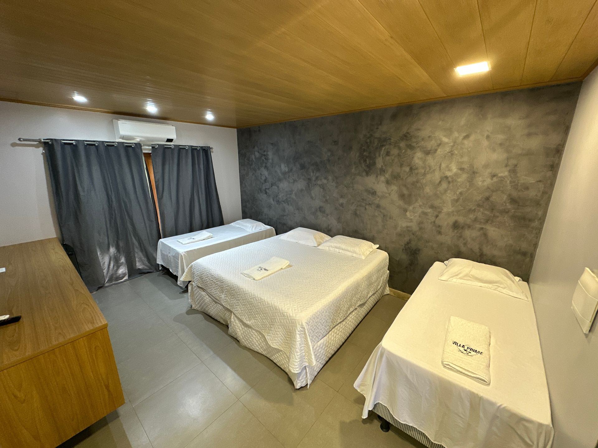 Um quarto de hotel com três camas e uma janela.