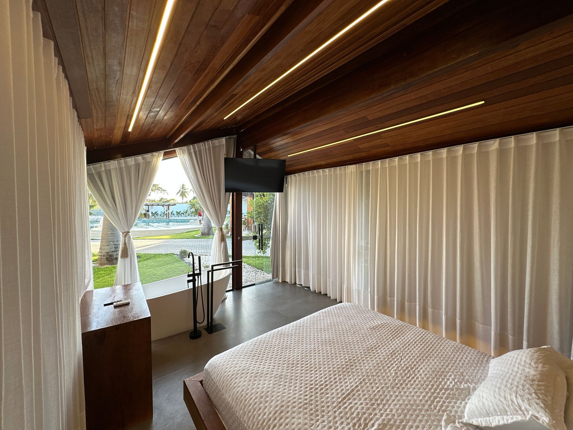 Um quarto com cama, televisão e banheira.