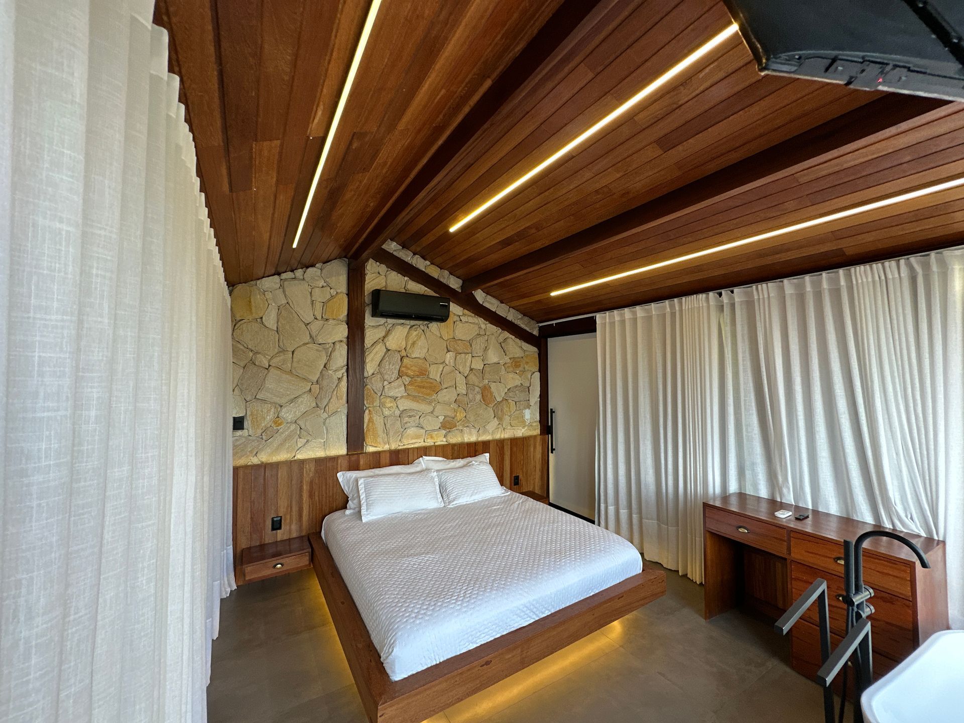 Um quarto com cama, escrivaninha e banheira.